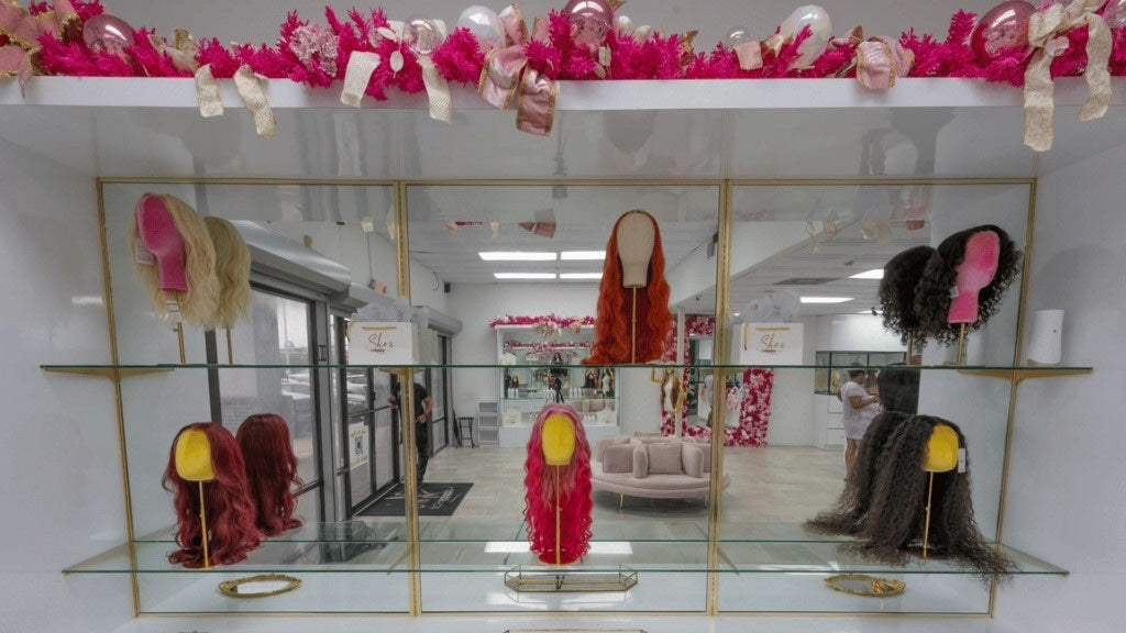 Gold glass wig display case with colorful wigs at Houston South